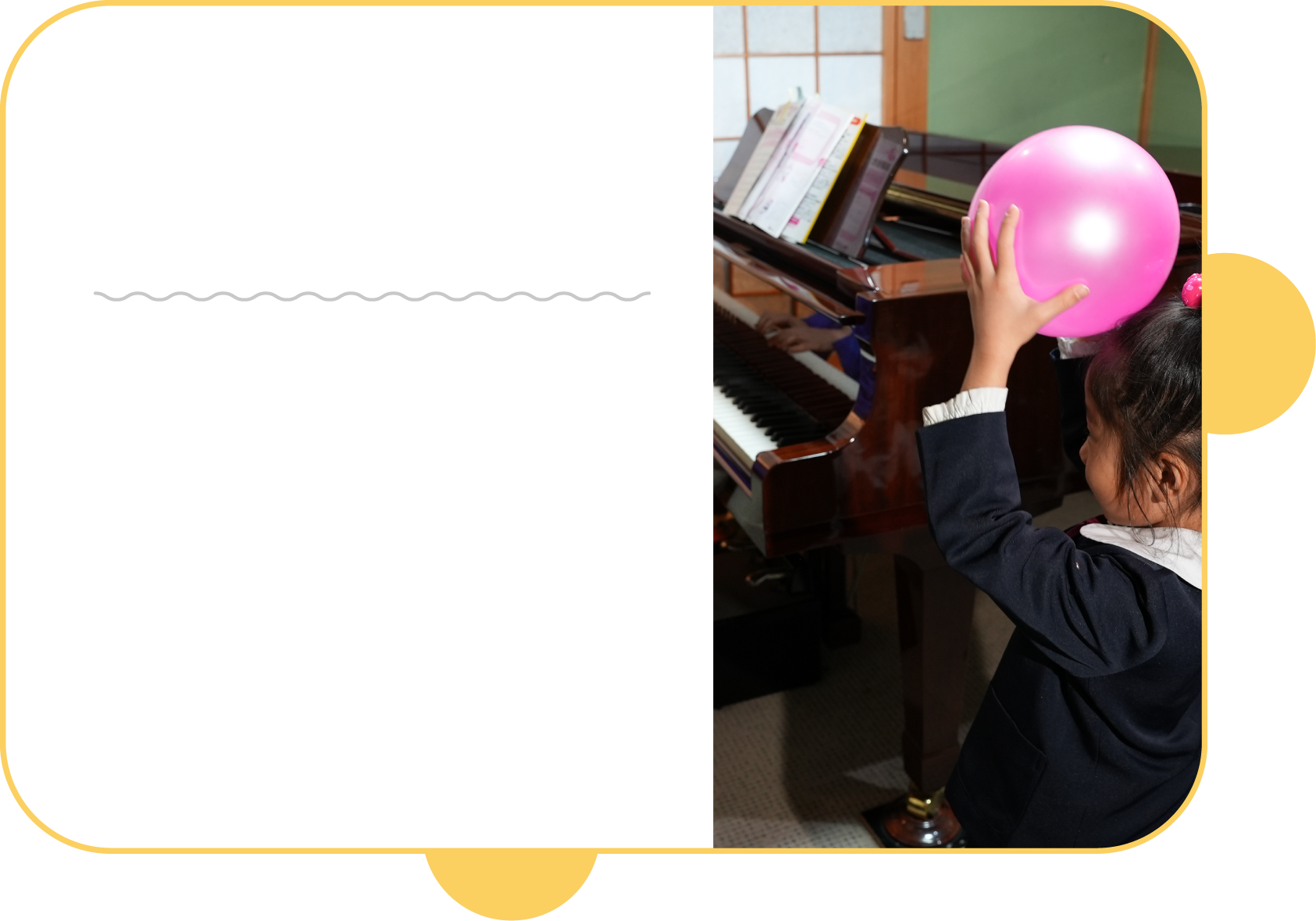 音楽教室で子供がピアノのリズムに合わせてボールを持ち上げている写真